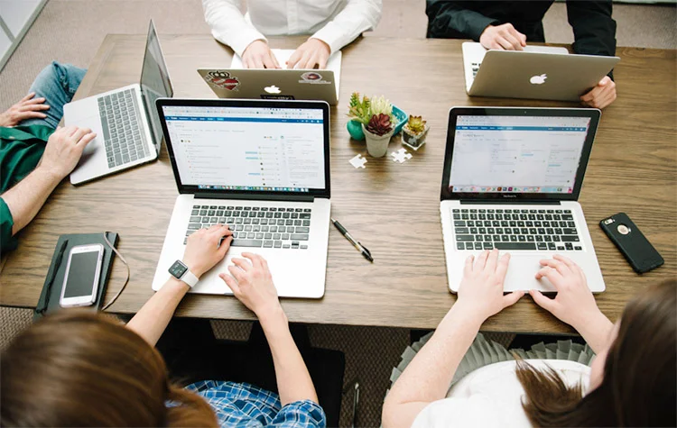 An overhead view of a development team working on laptops to build scalable e-commerce solutions for Shopify Plus.