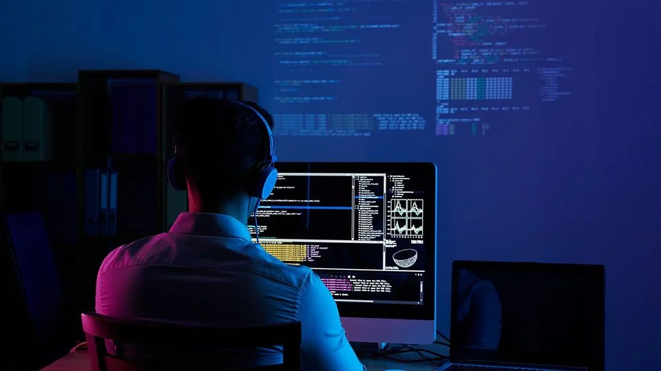 A professional Shopify developer working on complex liquid code and backend architecture in a dark-themed office setup. 